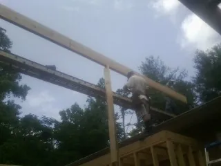 Carpenter setting a ridge beam over a new addition frame — Ice Dam Removal by Roofing Brothers in Easley