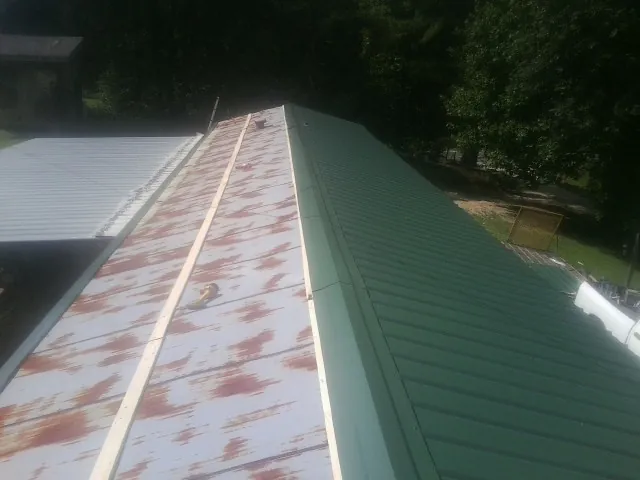 Old rusted panels beside newly installed green metal roofing — Wind Damage Roof Repair by Roofing Brothers in Easley