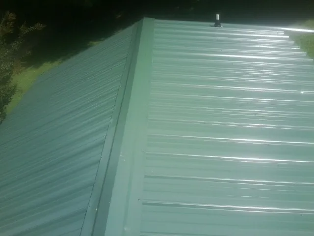 New green metal panels meeting at the ridge of a roof — Flat Roof Repair work by our crew in Easley