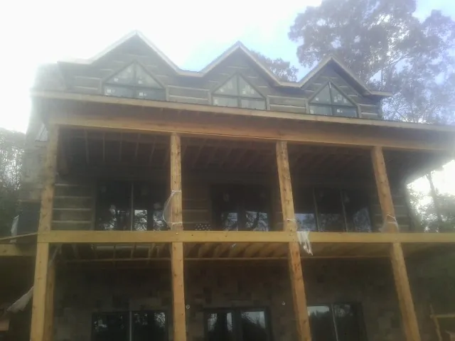 Dormers and porch framing on a large log home under construction — Roof Coating work by our crew in Easley