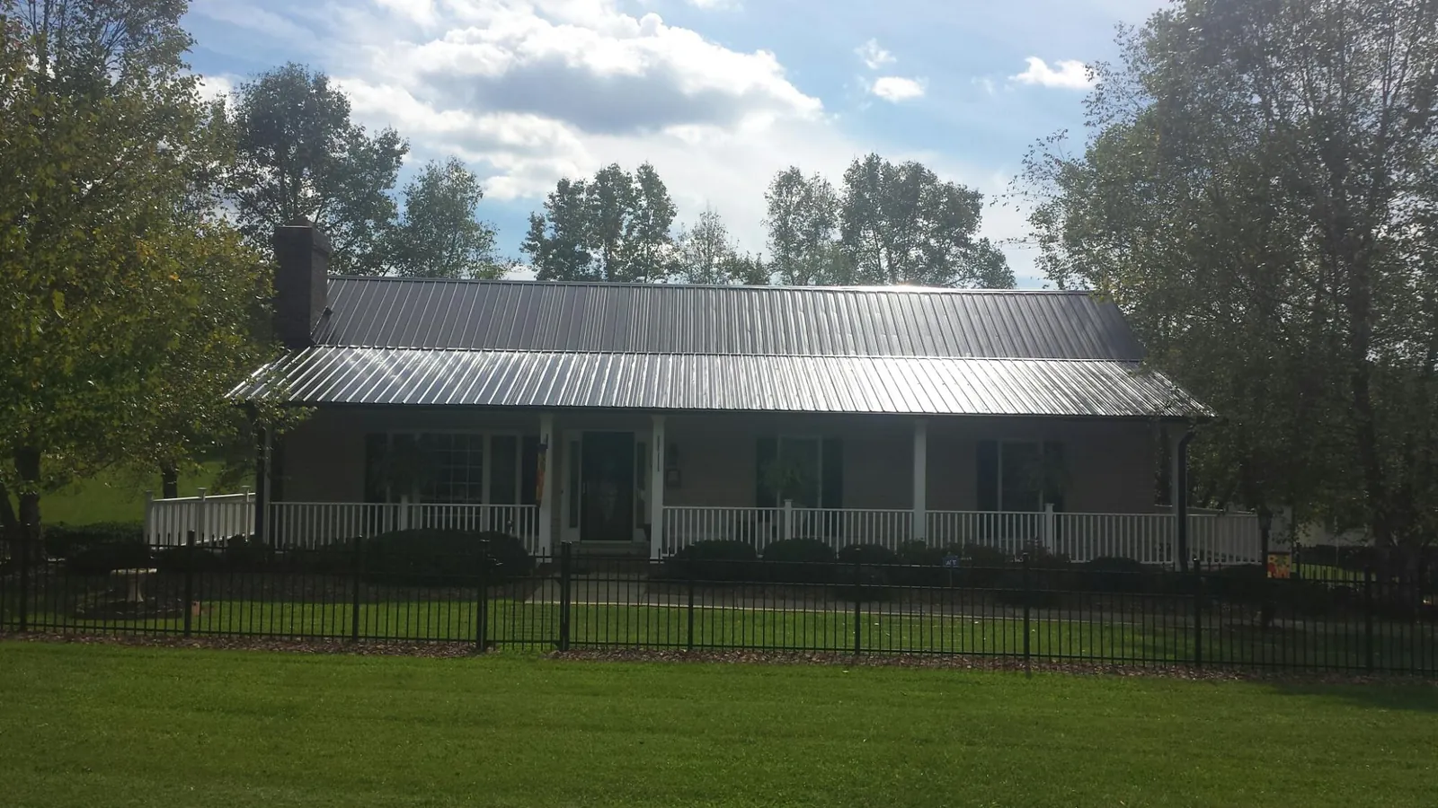 Gray metal roof on a brick ranch with a full width front porch — Gutter Guard Installation work by our crew in Easley