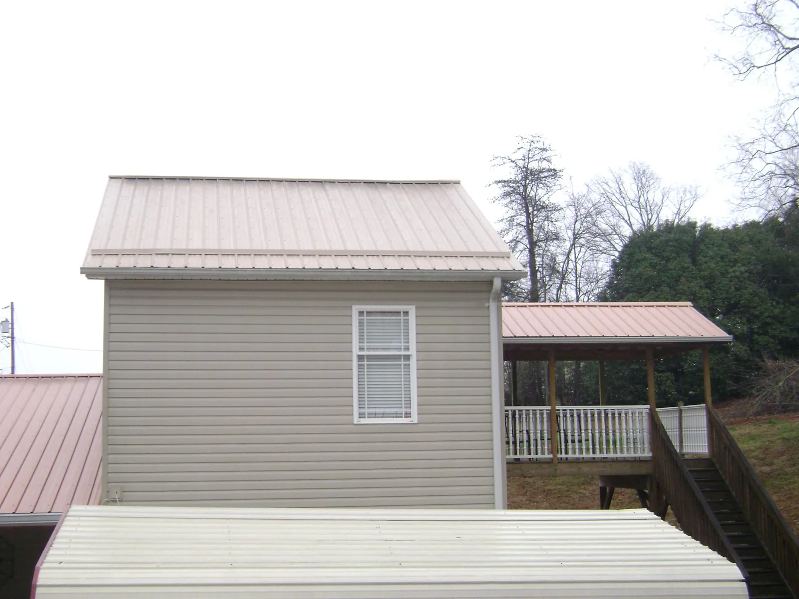 Tan metal roofs on a two story addition and attached porch, from a Roof Replacement job in Easley