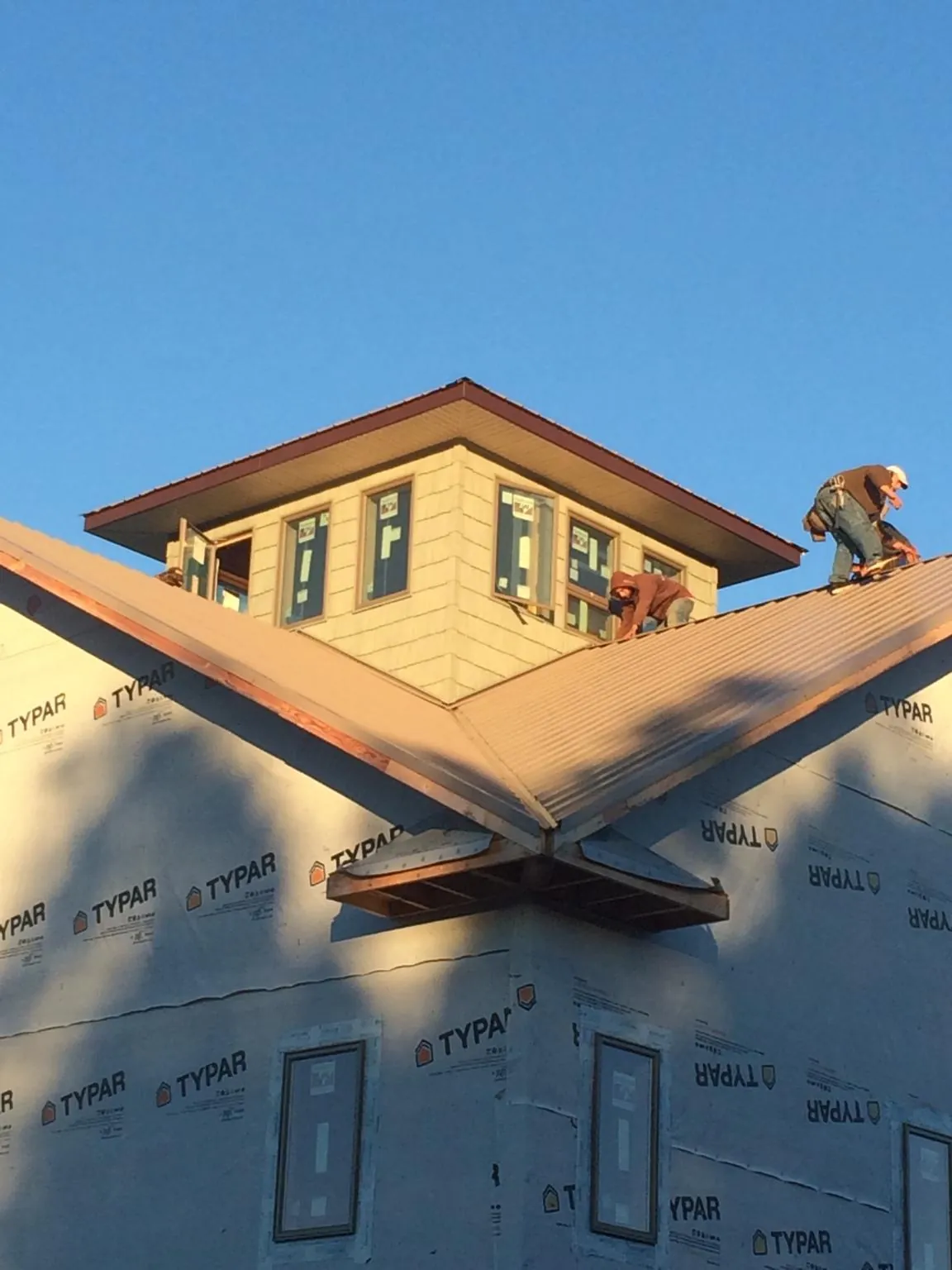 Roofers working around a rooftop cupola on a new metal roof at sunset — Roof Waterproofing in Easley by Roofing Brothers